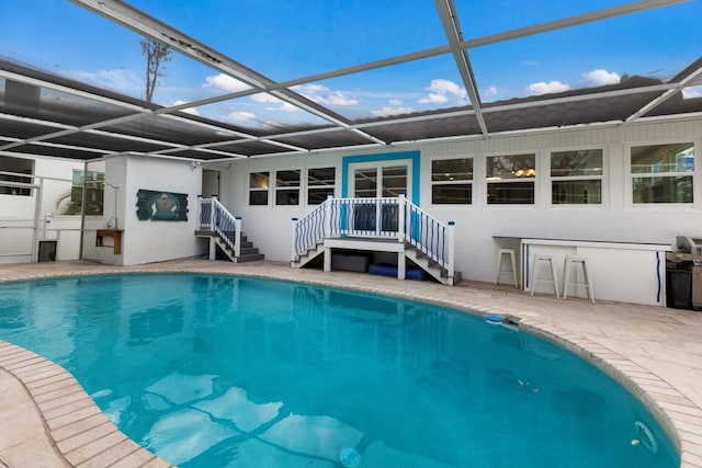 view of swimming pool featuring glass enclosure and a patio