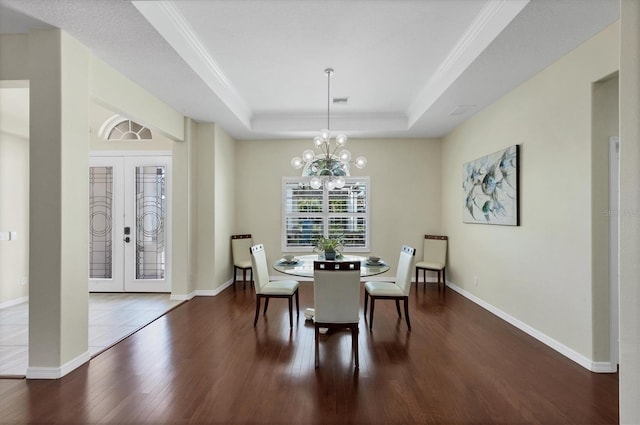 dining room with french doors, ornamental molding, a tray ceiling, an inviting chandelier, and dark hardwood / wood-style floors