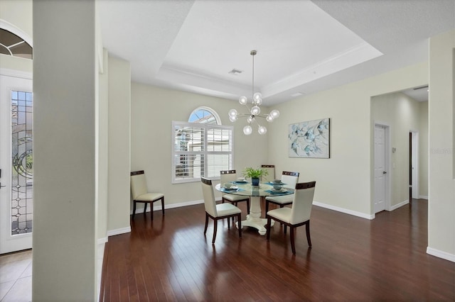 dining area featuring a notable chandelier, dark hardwood / wood-style floors, and a tray ceiling