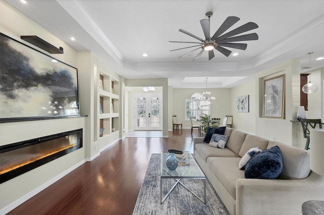 575 Fore Dr, Bradenton, FL 34208 - living room featuring a raised ceiling, wood finished floors, a ceiling fan, crown molding, and a glass covered fireplace