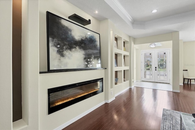 living room featuring french doors, dark wood-type flooring, built in features, a textured ceiling, and ornamental molding