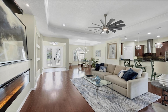 575 Fore Dr, Bradenton, FL 34208 - living room featuring a raised ceiling, dark wood finished floors, ceiling fan, ornamental molding, and a glass covered fireplace