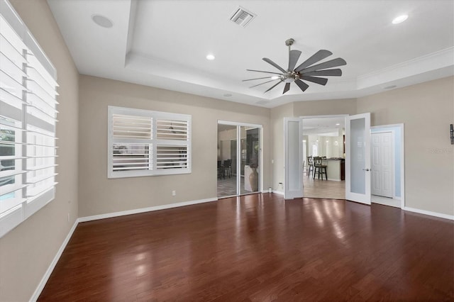 spare room with dark hardwood / wood-style floors, ceiling fan, a raised ceiling, and french doors