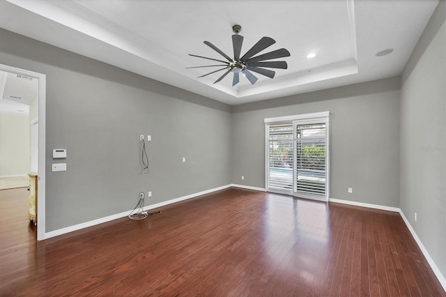 spare room with hardwood / wood-style floors, a raised ceiling, and ceiling fan