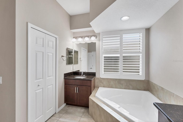 bathroom with tiled bath, tile patterned flooring, vanity, and a textured ceiling