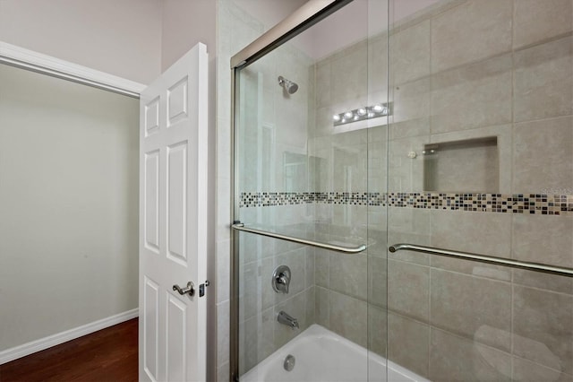 bathroom featuring hardwood / wood-style floors and bath / shower combo with glass door