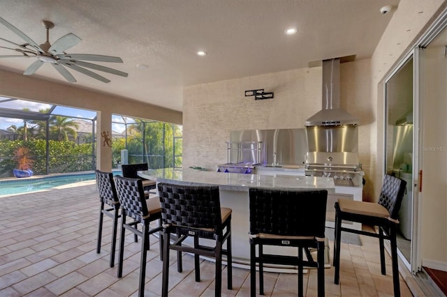 view of patio / terrace with an outdoor kitchen, area for grilling, a lanai, ceiling fan, and an outdoor bar