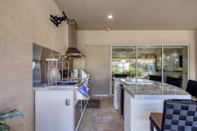 575 Fore Dr, Bradenton, FL 34208 - kitchen with stone finish floors, wall chimney range hood, a kitchen island, a kitchen breakfast bar, and baseboards