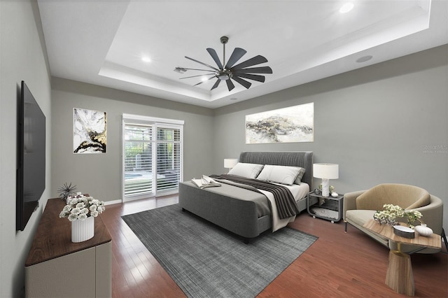 bedroom featuring access to exterior, a raised ceiling, ceiling fan, and dark wood-type flooring