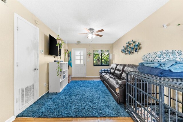 living room featuring ceiling fan, a textured ceiling, and hardwood / wood-style flooring