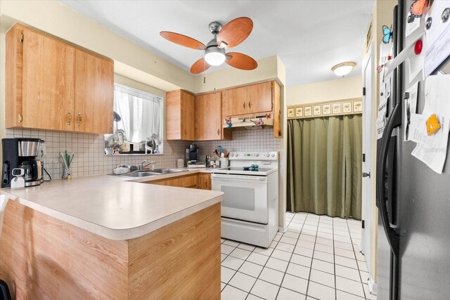 kitchen with kitchen peninsula, stainless steel fridge, backsplash, sink, and white range with electric cooktop