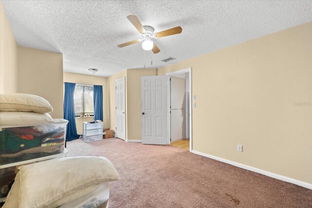 carpeted bedroom featuring ceiling fan and a textured ceiling