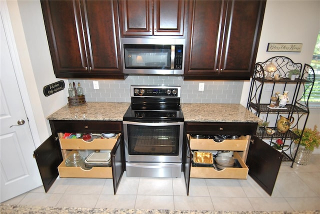 kitchen with backsplash, appliances with stainless steel finishes, light tile patterned floors, and light stone countertops