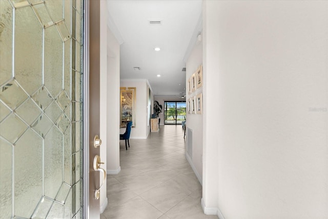 hall featuring light tile patterned floors and ornamental molding