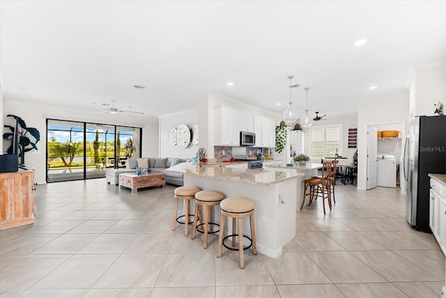 kitchen featuring white cabinets, light stone counters, stainless steel appliances, and a wealth of natural light