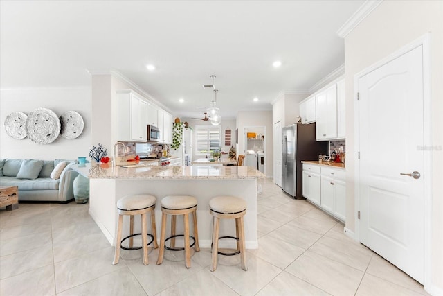 kitchen featuring pendant lighting, white cabinets, light stone countertops, appliances with stainless steel finishes, and kitchen peninsula