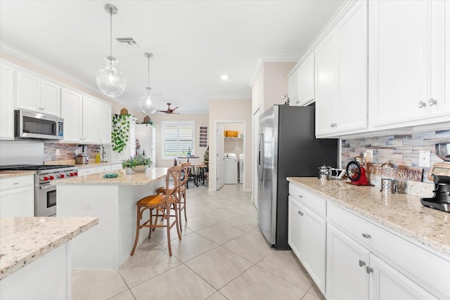 kitchen featuring washer and clothes dryer, a kitchen island, white cabinetry, and stainless steel appliances