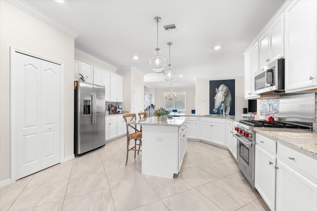 kitchen with kitchen peninsula, appliances with stainless steel finishes, ornamental molding, a breakfast bar, and a center island