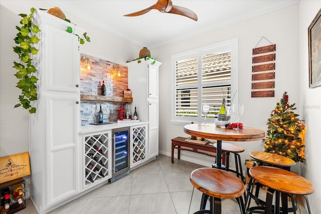 bar with white cabinets, light tile patterned floors, beverage cooler, and ornamental molding