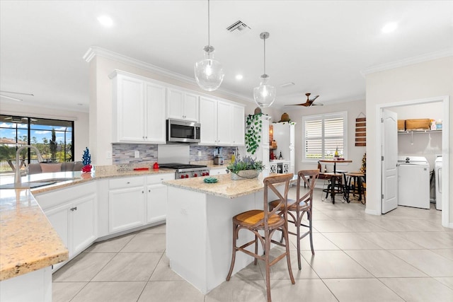 kitchen with sink, a healthy amount of sunlight, stainless steel appliances, pendant lighting, and washer and clothes dryer