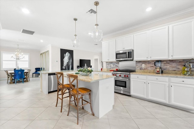 kitchen with a center island, white cabinets, crown molding, a kitchen bar, and stainless steel appliances