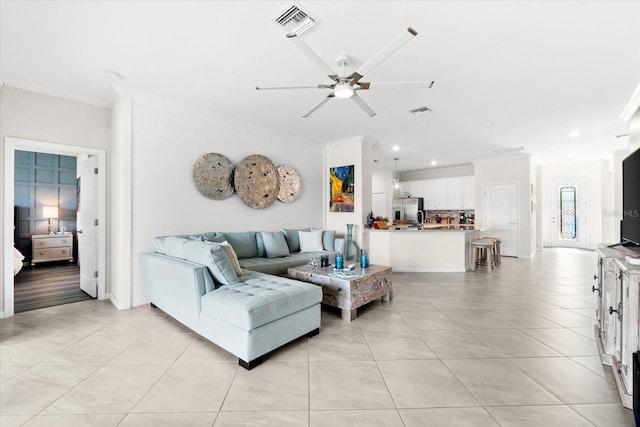 living room with ceiling fan, ornamental molding, and light tile patterned flooring