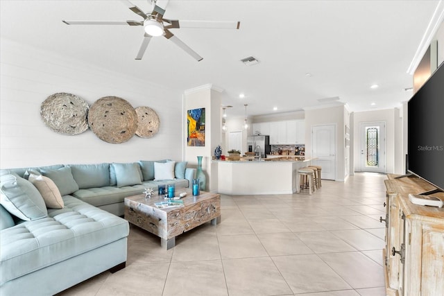 tiled living room featuring ceiling fan and ornamental molding