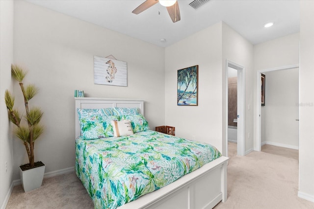 bedroom featuring ceiling fan, light colored carpet, and connected bathroom