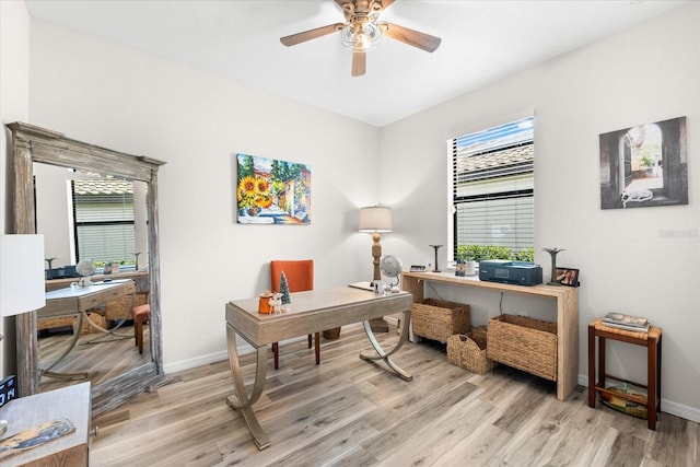 home office with light hardwood / wood-style floors and ceiling fan