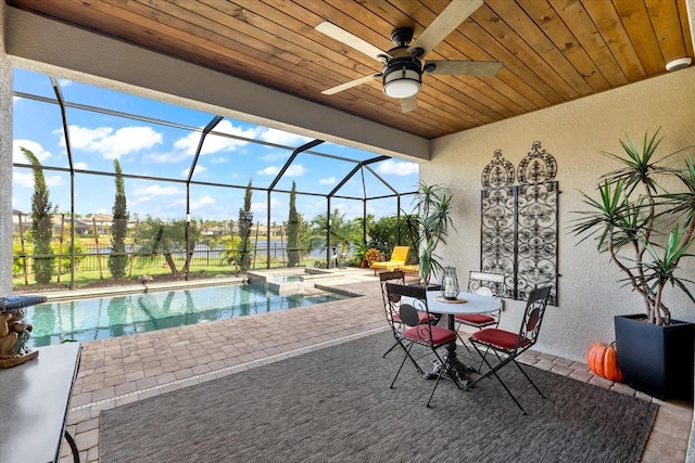 view of pool with an in ground hot tub, a patio, glass enclosure, and ceiling fan