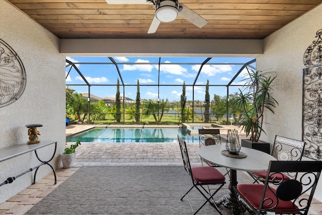 view of pool with glass enclosure, ceiling fan, a patio area, and an in ground hot tub