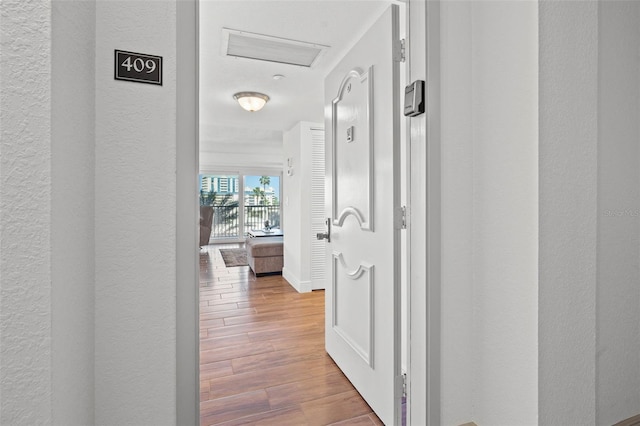 corridor featuring baseboards, a textured wall, and wood finished floors