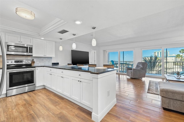 kitchen with open floor plan, appliances with stainless steel finishes, a peninsula, light wood-style floors, and white cabinets