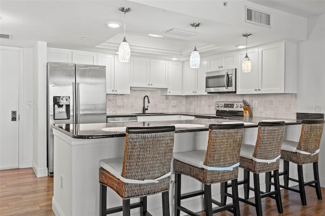 kitchen with visible vents, a peninsula, a sink, appliances with stainless steel finishes, and white cabinetry