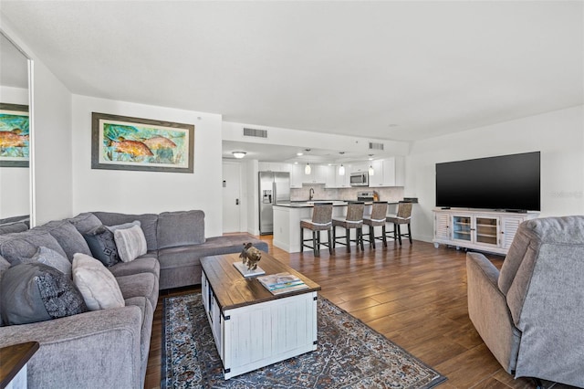 living area with visible vents and dark wood-style floors