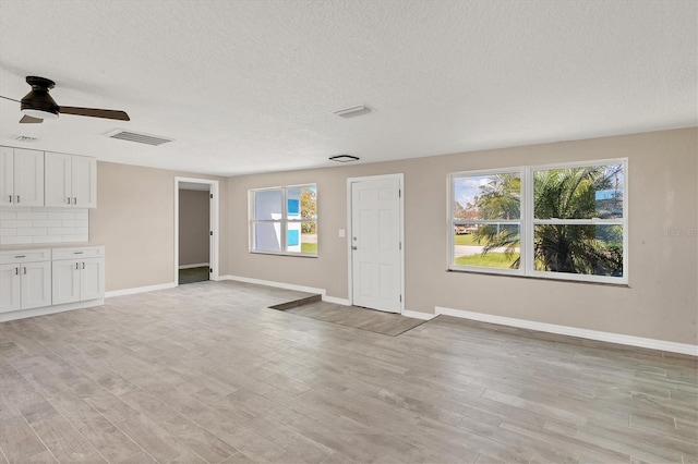 unfurnished living room featuring light hardwood / wood-style floors, a healthy amount of sunlight, and a textured ceiling