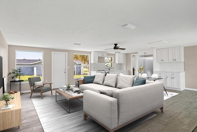 living room with a textured ceiling, plenty of natural light, hardwood / wood-style flooring, and ceiling fan