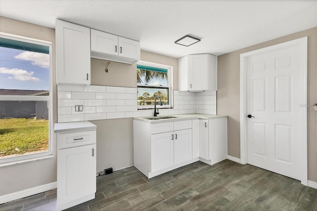 kitchen with white cabinets, dark hardwood / wood-style flooring, sink, and backsplash