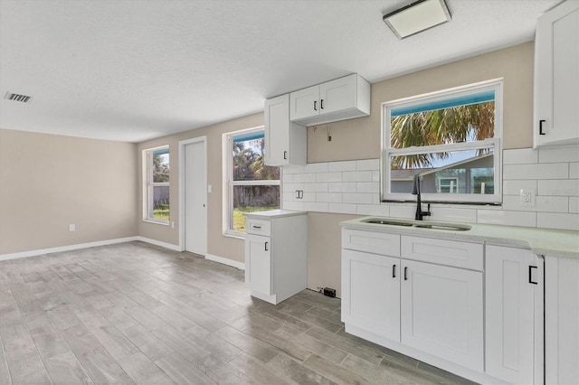 kitchen featuring white cabinets, a wealth of natural light, sink, and light hardwood / wood-style flooring