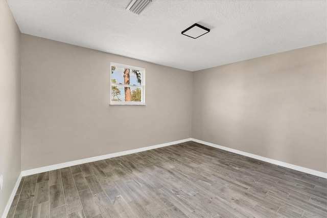 unfurnished room with hardwood / wood-style floors and a textured ceiling