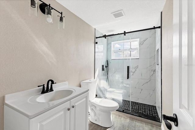 bathroom with wood-type flooring, toilet, a textured ceiling, vanity, and a shower with shower door