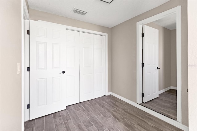 unfurnished bedroom with a textured ceiling, hardwood / wood-style flooring, and a closet