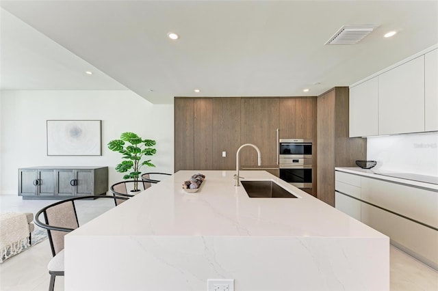 111 Golden Gate Pt Unit 402, Sarasota, FL 34236 - kitchen featuring a sink, modern cabinets, a large island with sink, recessed lighting, and stainless steel double oven