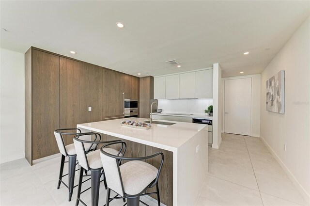 111 Golden Gate Pt Unit 402, Sarasota, FL 34236 - kitchen featuring modern cabinets, a sink, a kitchen bar, light countertops, and a kitchen island with sink