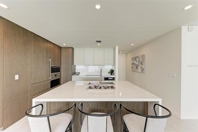 111 Golden Gate Pt Unit 402, Sarasota, FL 34236 - kitchen featuring modern cabinets, a sink, light tile patterned flooring, a kitchen bar, and recessed lighting