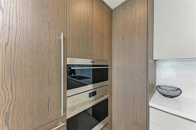 kitchen featuring stainless steel double oven, light countertops, and modern cabinets