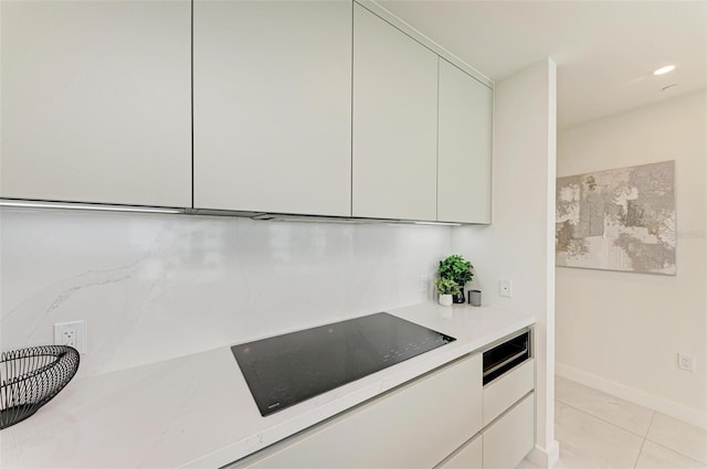 kitchen with black electric stovetop, light tile patterned flooring, white cabinets, light countertops, and modern cabinets