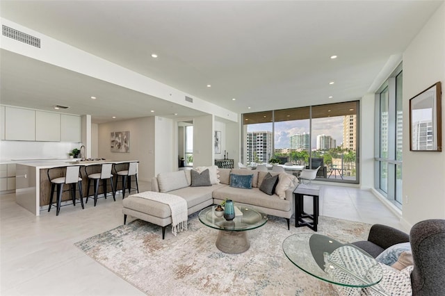 living area with a wall of windows, recessed lighting, visible vents, and a city view