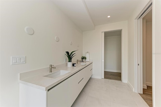 kitchen featuring light countertops, white cabinetry, a sink, modern cabinets, and baseboards