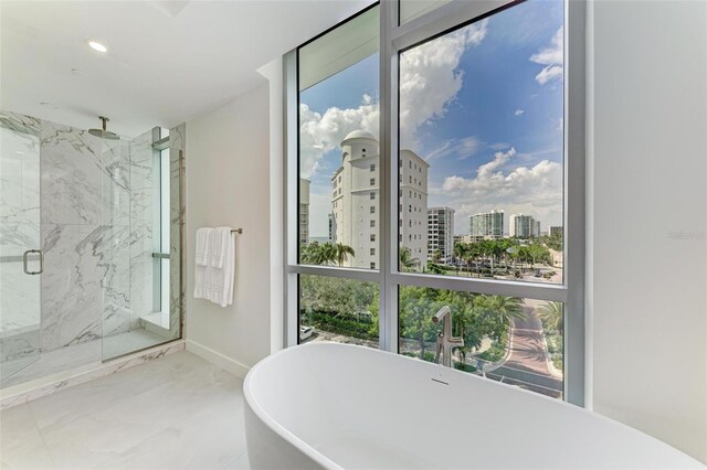 111 Golden Gate Pt Unit 402, Sarasota, FL 34236 - bathroom featuring healthy amount of natural light, a marble finish shower, a soaking tub, and baseboards
